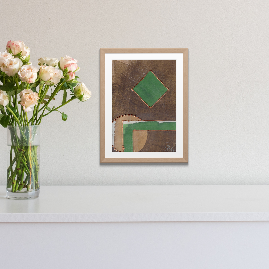 Framed abstract art piece on a wall with a vase of flowers next to it.
