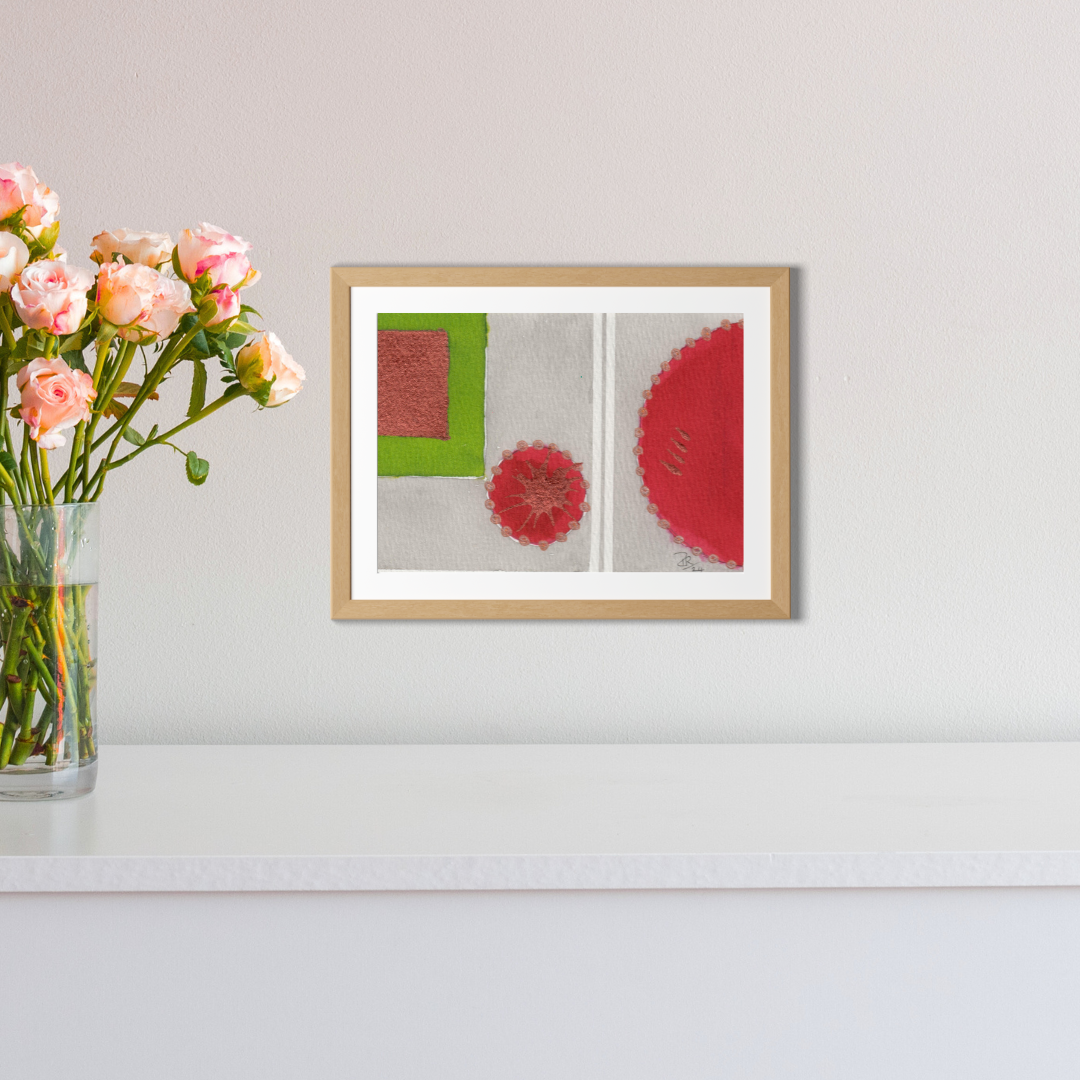 Framed abstract artwork on a wall with a vase of flowers next to it.