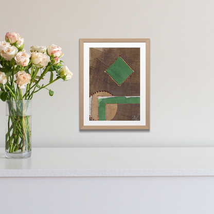 Framed abstract art piece on a wall with a vase of flowers next to it.