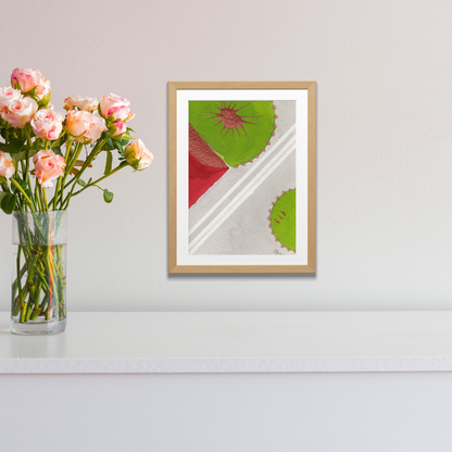 Framed abstract artwork with geometric design on a white wall next to a vase of flowers.