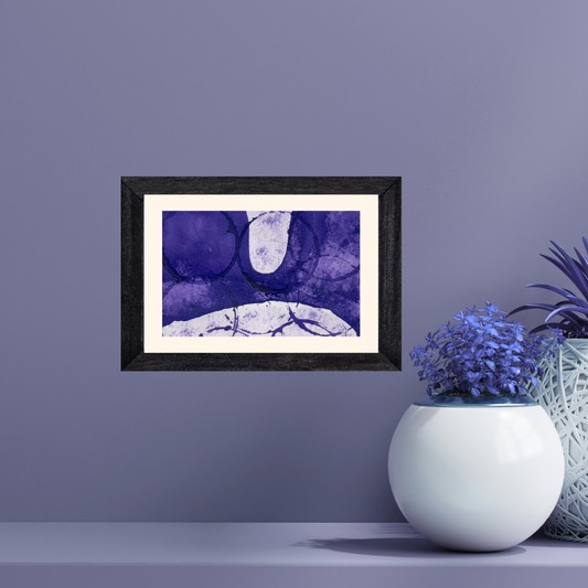 Framed abstract art piece on a purple wall with decorative plants.