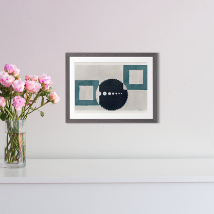 Framed abstract art piece on a wall with a vase of pink flowers to the left.