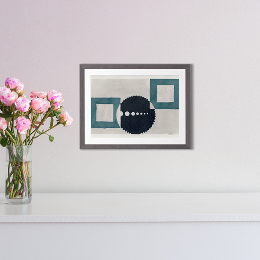 Framed abstract art piece on a wall with a vase of pink flowers to the left.