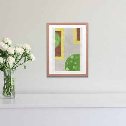 Framed abstract art with geometric shapes on a wall next to a vase of flowers.