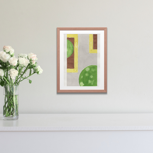 Framed abstract art with geometric shapes on a wall next to a vase of flowers.