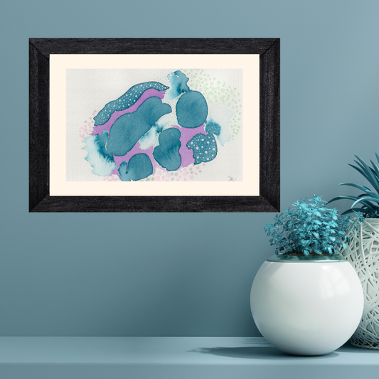 Framed artwork with blue abstract design on a light blue wall, next to a white vase with plants.