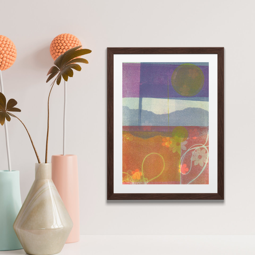 Framed abstract artwork on a wall above a wooden surface with a plant.