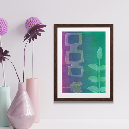 Framed abstract art piece on a wall next to a potted plant