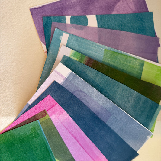 Set of colorful paper collage scraps arranged on a beige surface