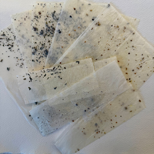 Tissue paper pieces with black specks on a white background