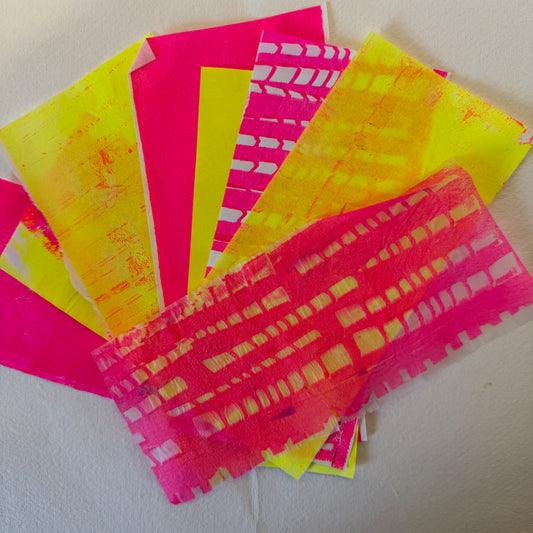 Neon pink and yellow patterned paper sheets on a light background